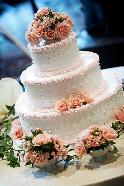 Wedding Cake A three tiered wedding cake, shallow depth of field with the focus on the center of the cake. Pink roses on top.